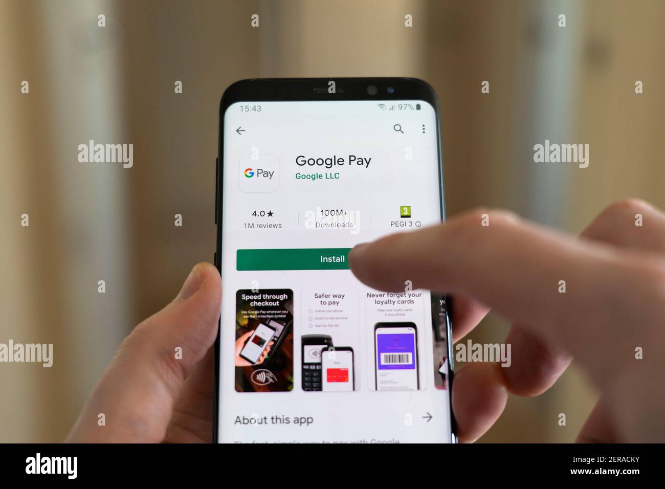 A man installing the Google Pay app on a smartphone by selecting the install button with his finger. Google Pay is a digital wallet platform Stock Photo