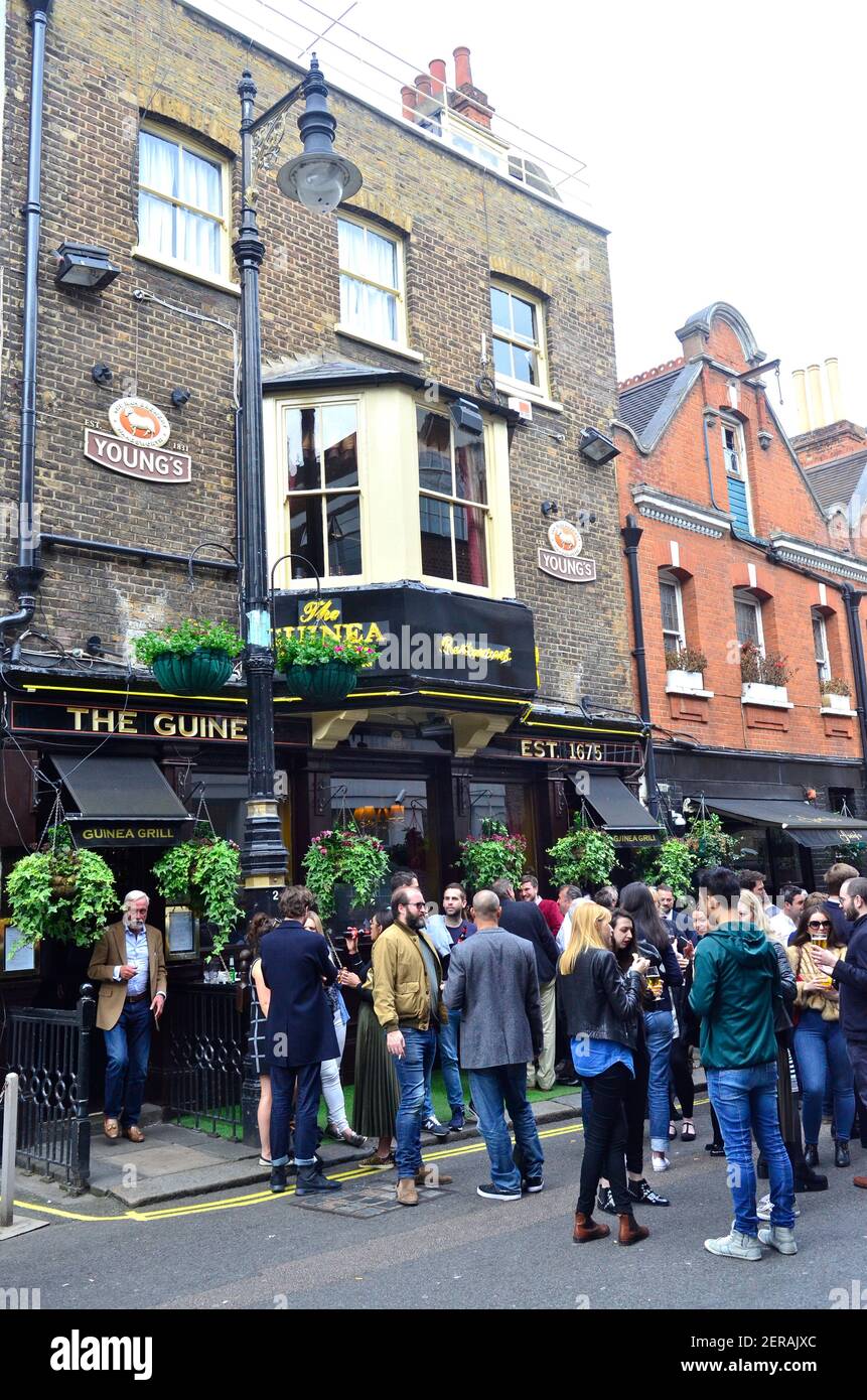 People drinking outside The Guinea pub in Mayfair, London Stock Photo