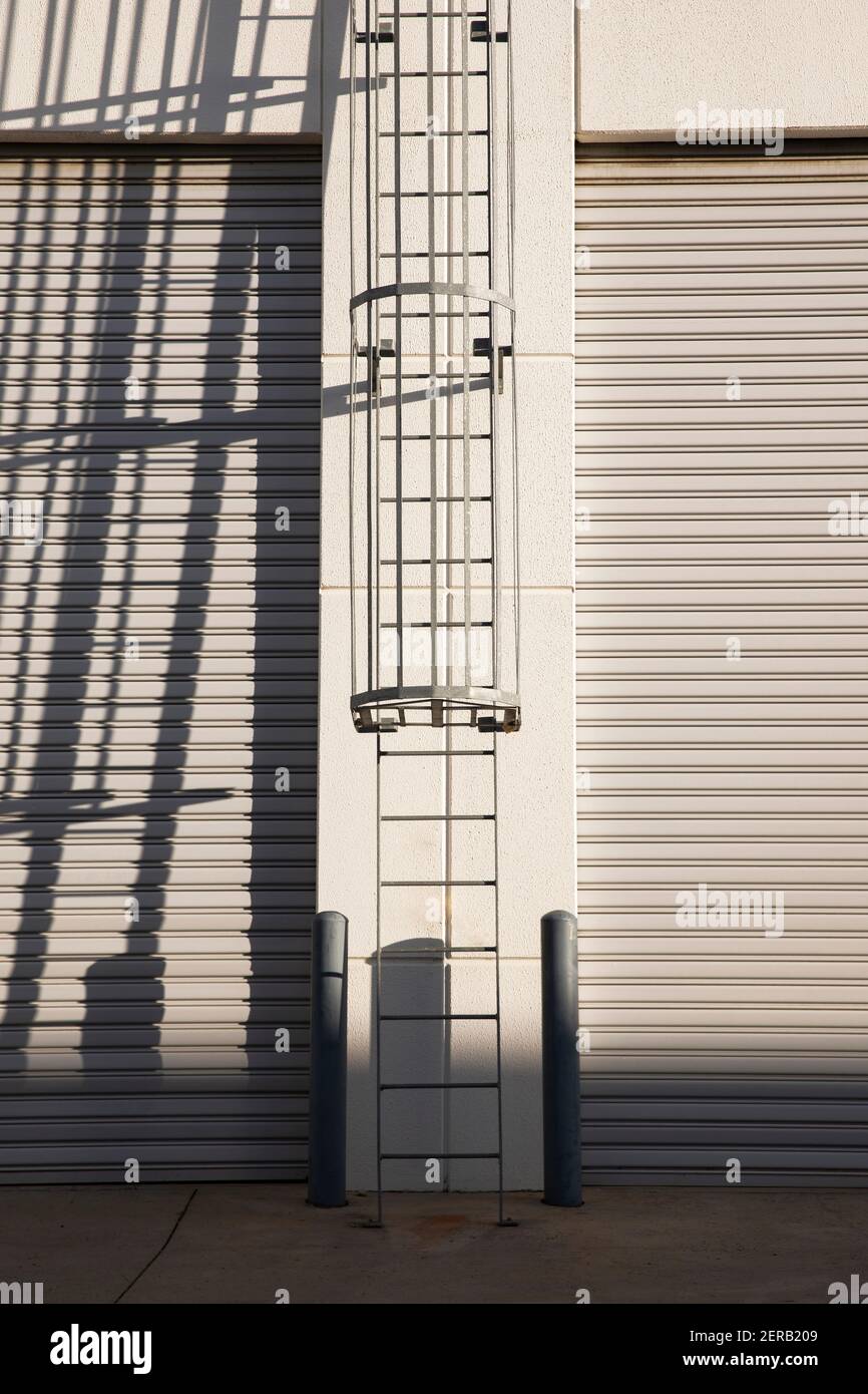 Industrial roof access ladder dispatch warehouse roller doors. Stock Photo