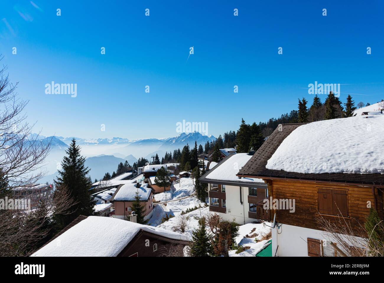 Unique panoramic alpine skyline view of Rigi resort. Snowed Chalets, wooden lodging cabins, hotels, mount Pilatus, blue sky. Mount Rigi, Weggis, Lucer Stock Photo