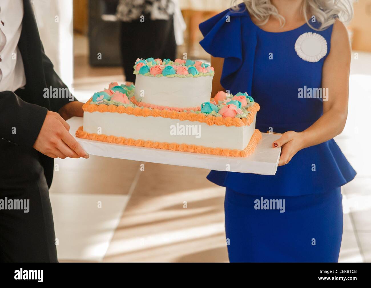 Man and woman walk with birthday cake in hand at wedding, close-up. Stock Photo