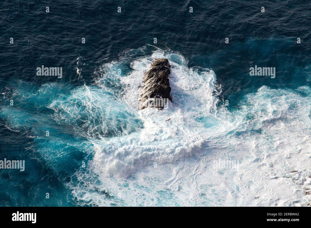 Waves crash over and around rocks in the Caribbean Sea, as seen from the peak of the island of Redonda, Antigua and Barbuda, Caribbean. Stock Photo