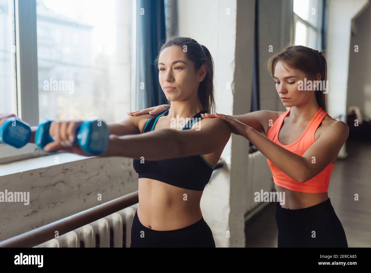 Young woman personal trainer helping with workout at gym Stock Photo ...