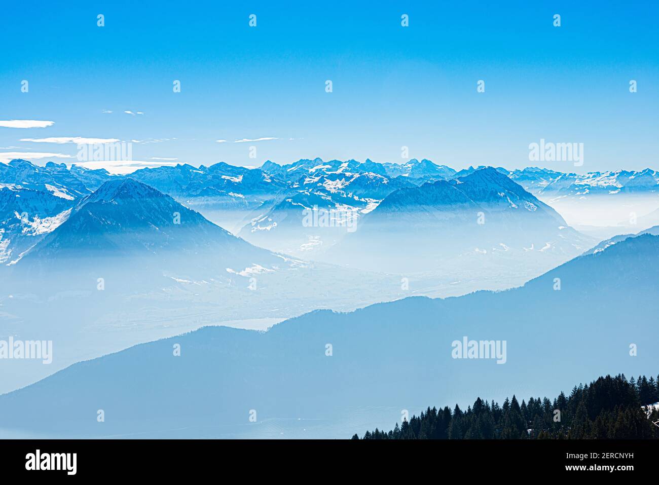 Unique panoramic alpine skyline aerial landscape view of misty iced Swiss Alps peaks in blue sky. Mount Rigi Switzerland in spring. Travel concept. Stock Photo