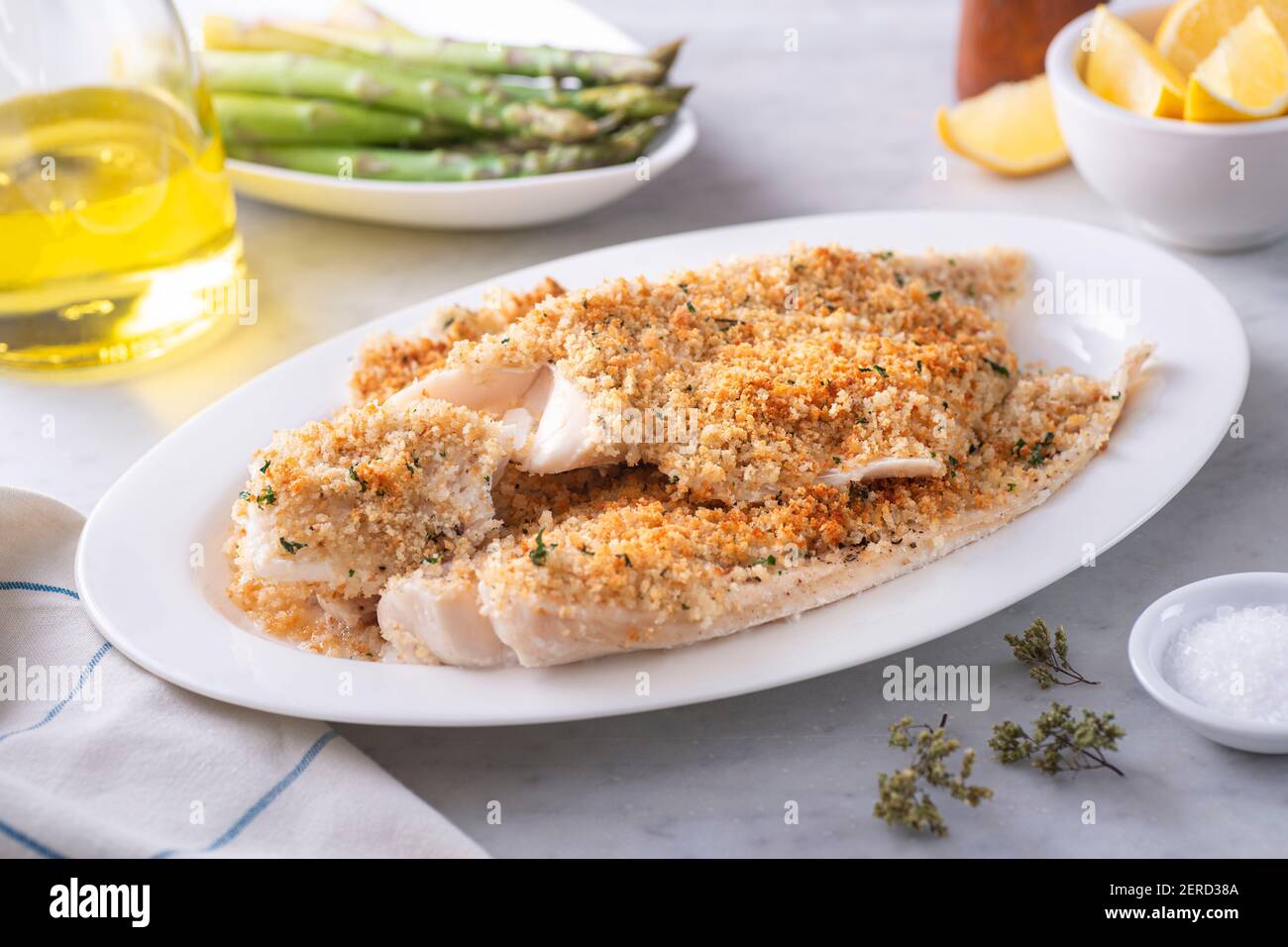 A plate of delicious panko breadcrumb crusted baked haddock with asparagus and lemon. Stock Photo
