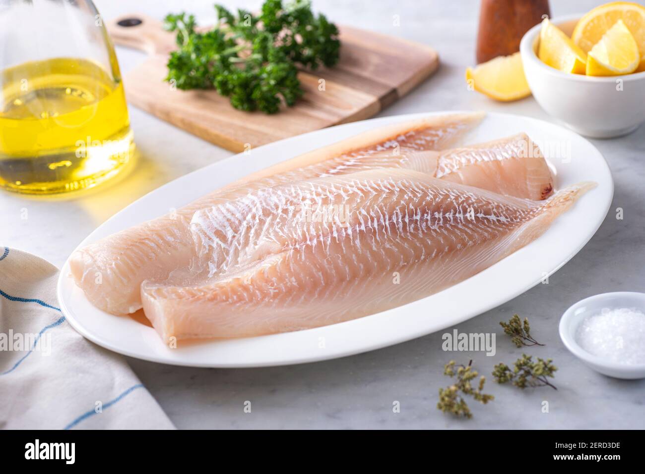 Fresh Icelandic Haddock Fillets on a plate with lemon and parsley. Stock Photo