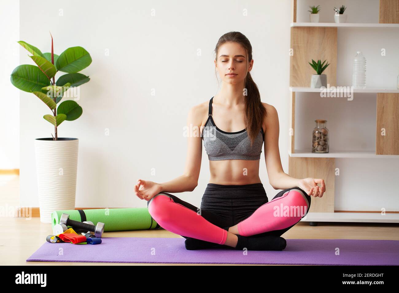 Attractive young woman sitting on lotus position on floor with eyes ...