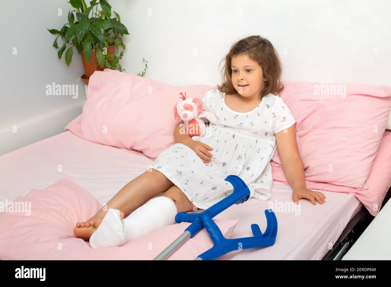 A relaxed teenage girl lies on the bed after receiving a plaster cast on her leg in an orthopedic emergency room. The child has a broken leg, broken Stock Photo