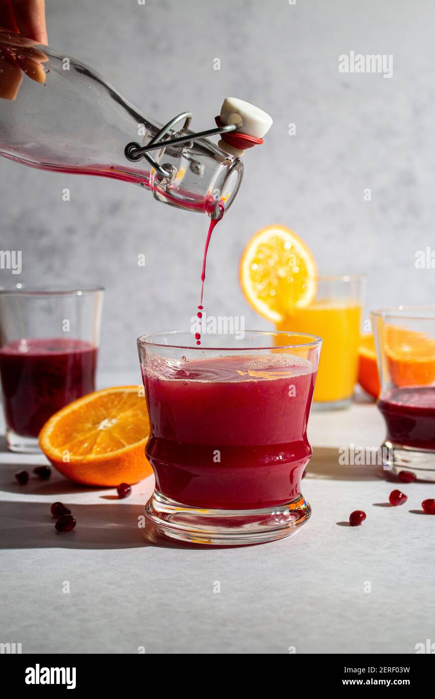 Fresh squeezed pomegranate juice being poured into orange juice Stock Photo