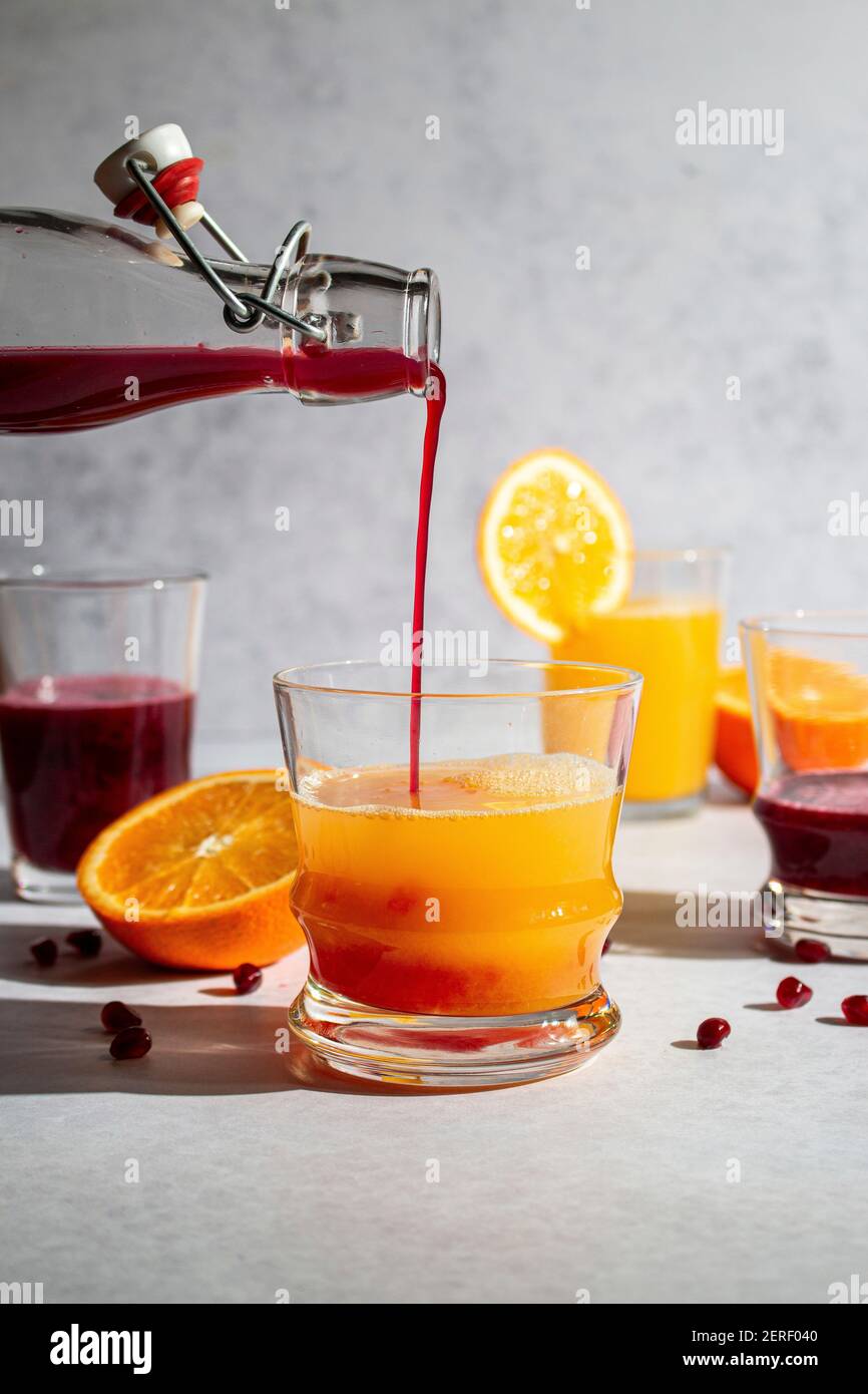 Fresh squeezed pomegranate juice being poured into orange juice Stock