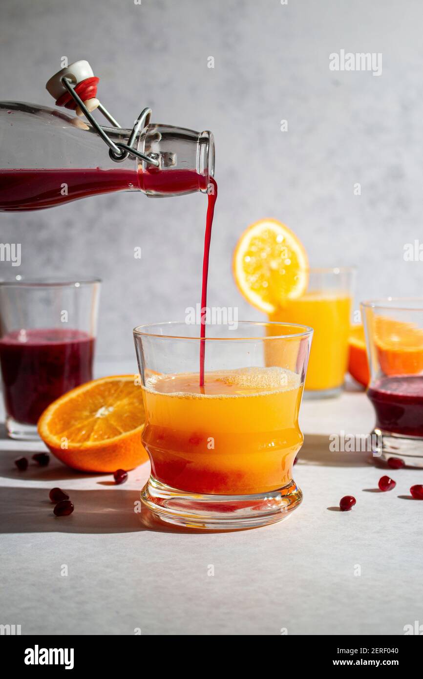 Fresh squeezed pomegranate juice being poured into orange juice Stock Photo