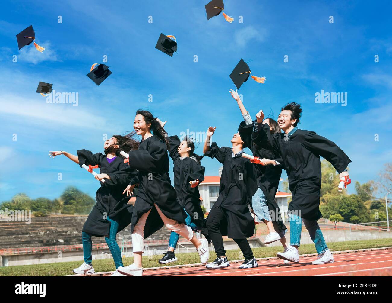 Happy Students with congratulations throwing graduation hats in the air ...