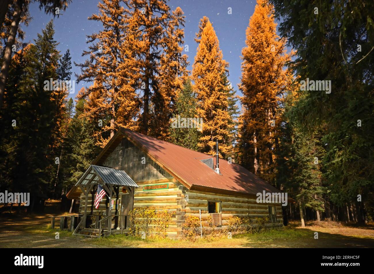 The Yaak Community Hall at night surrounded by western larch during a full moon in fall. Yaak Valley, northwest Montana. (Photo by Randy Beacham) Stock Photo