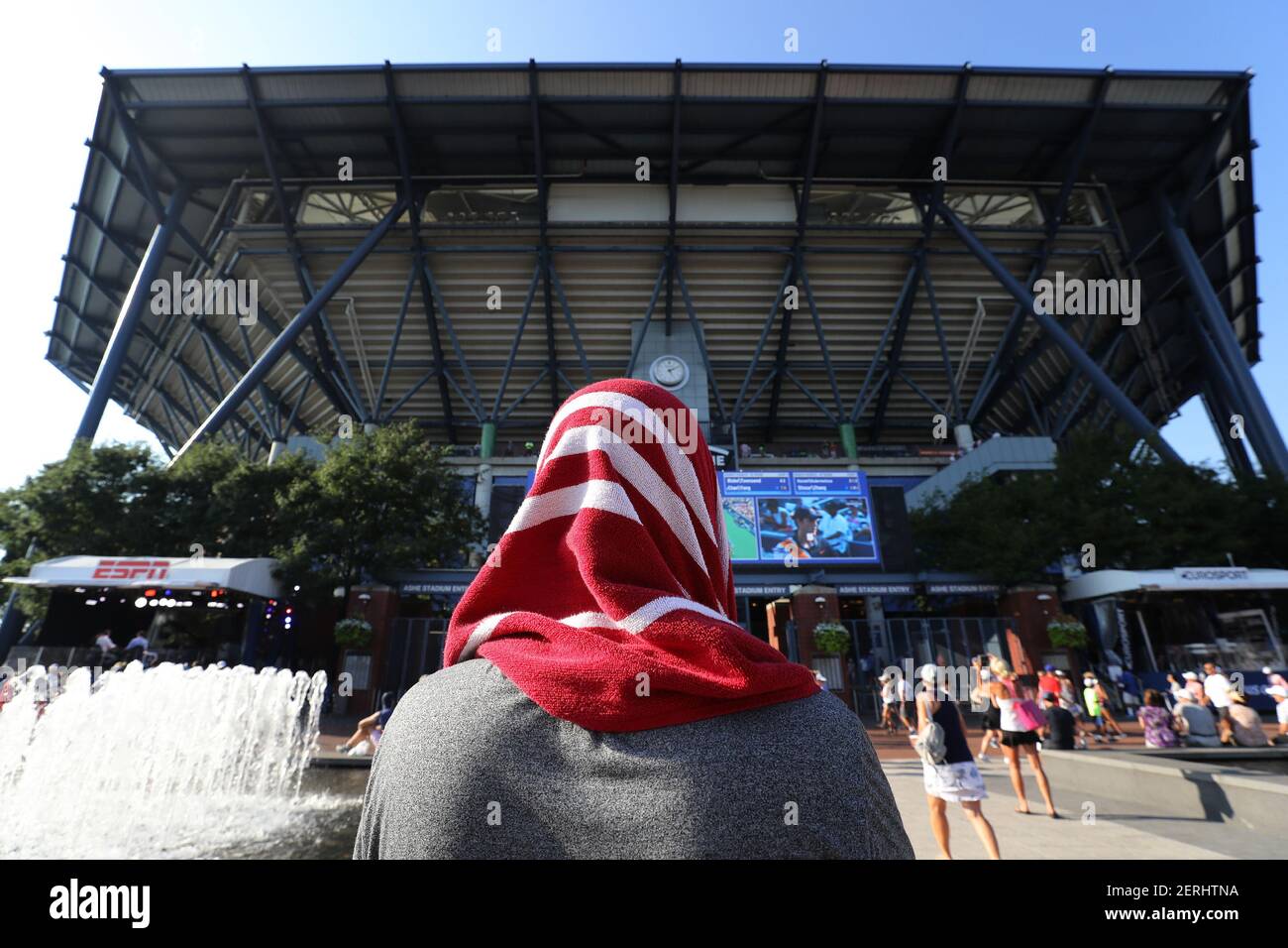 With temperatures reaching above ninety degrees, a man wears a damp towel  over his head to keep himself cool as he watches tennis matches on big  screens at the 2018 US Open