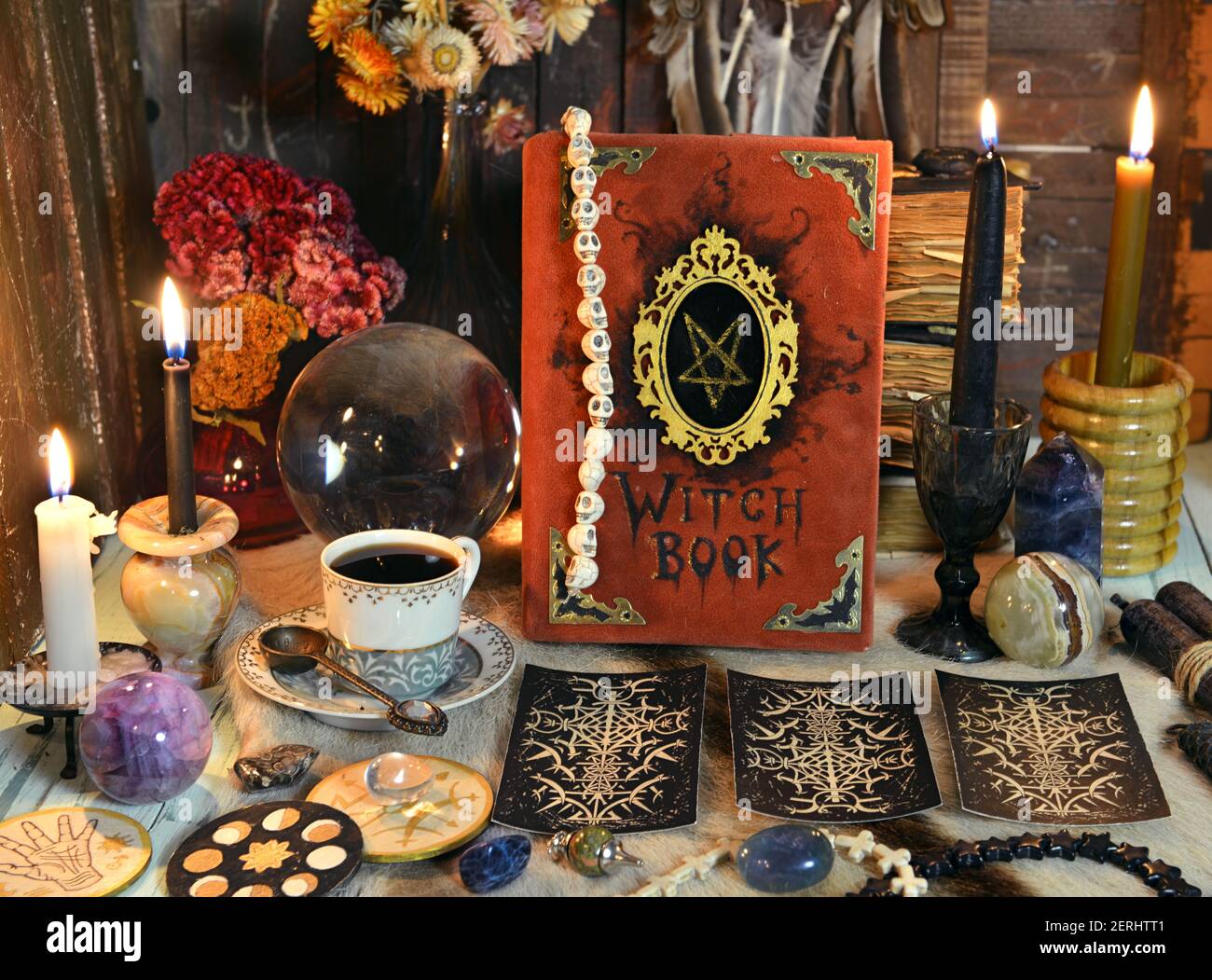 Red witch book with tarot cards, tea cup, black candle and magic ritual