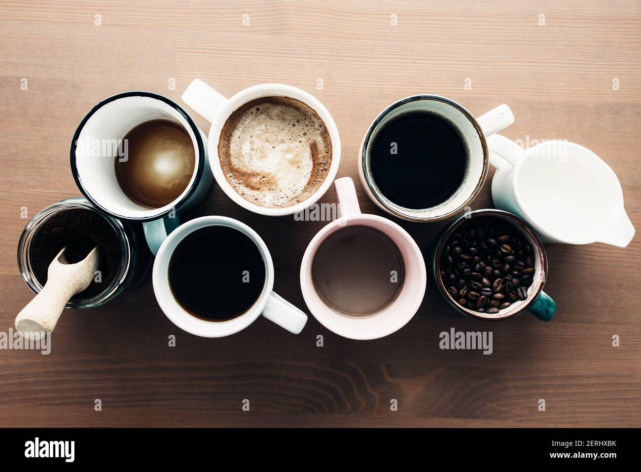 Multiple coffee cups, milk, beans and ground coffee in jar on wooden background. High quality photo Stock Photo