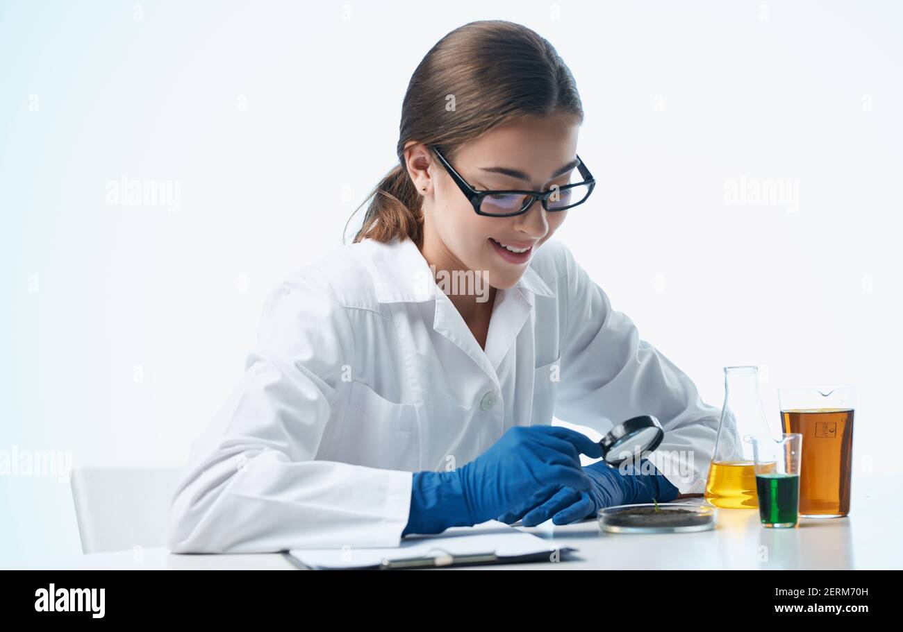 a nurse in a lab coat and blue gloves with a flask in her hand chemical ...