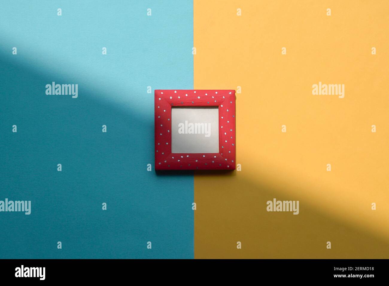 Design concept - top view of red photo frame isolated on blue and yellow background for mockup. Copy space. Stock Photo