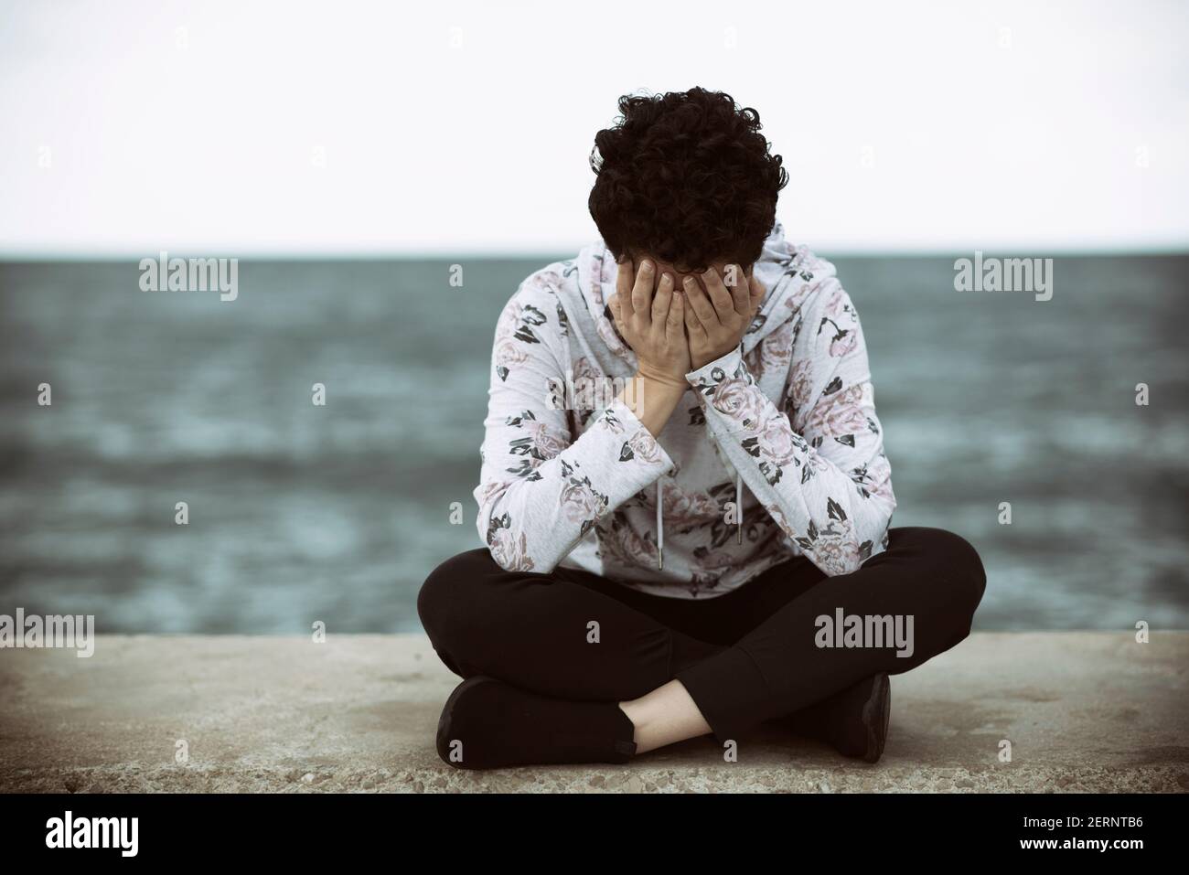 Sad woman wat on the beach head in hands crying Stock Photo