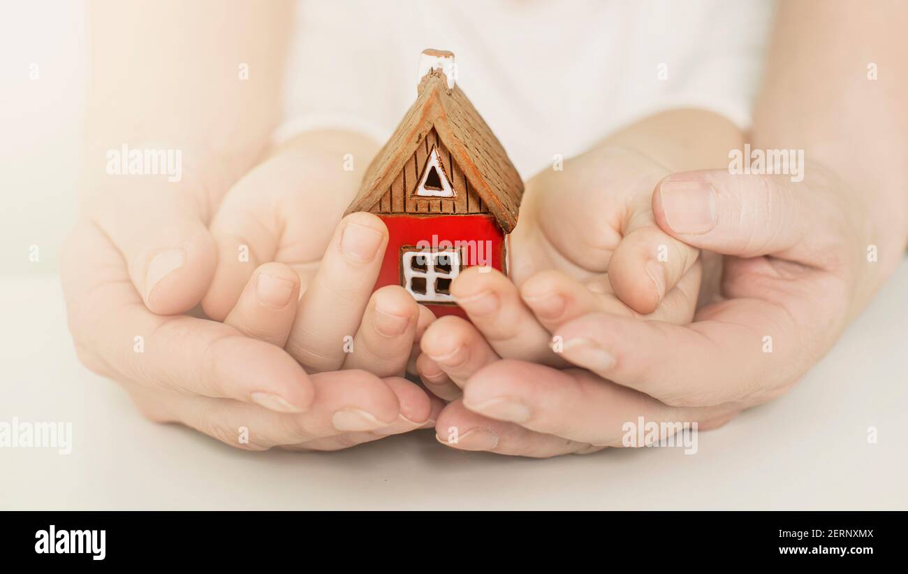 real estate and family home concept - closeup picture of child and female hands holding red paper house with family. High quality photo Stock Photo