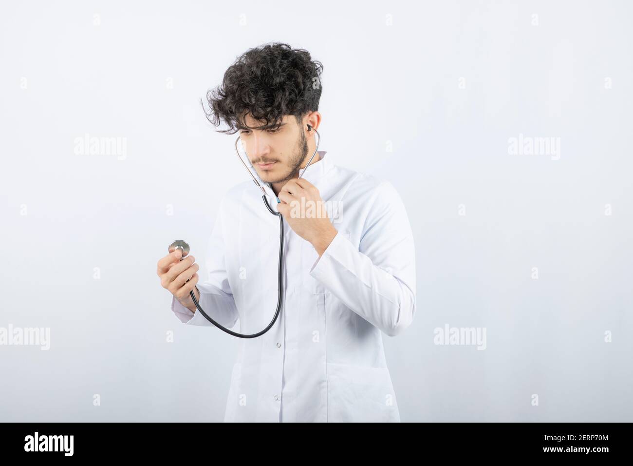 Portrait of a male doctor holding a stethoscope and listening Stock ...