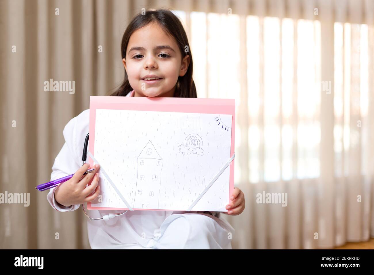 Little child dressed as a doctor showing a drawing she has just made. Space for text. Stock Photo