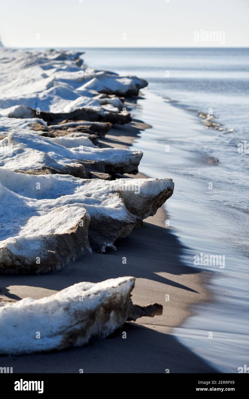 Winter seaside landscape, melting ice and snow on the beach. Stock Photo