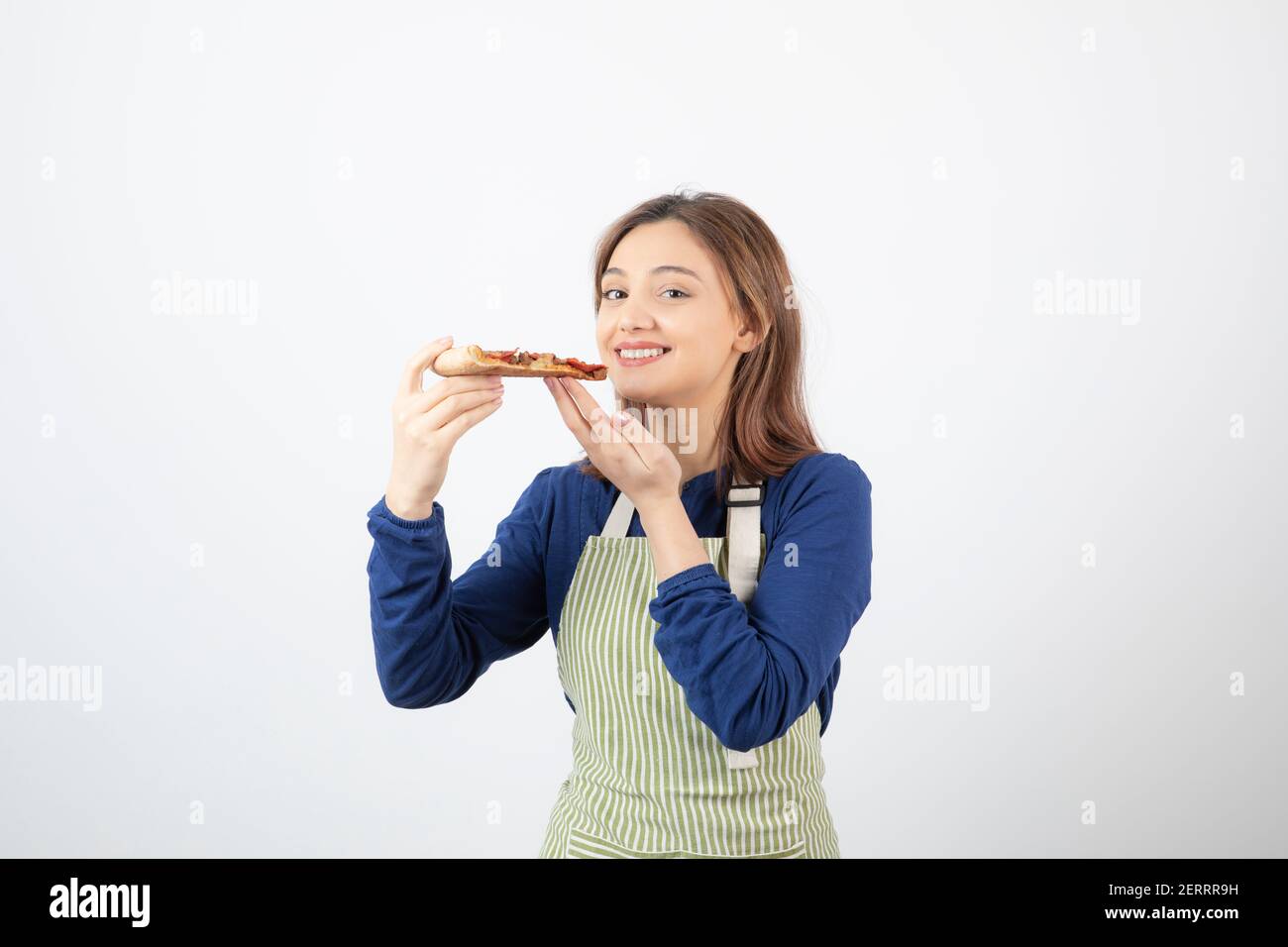 Portrait of female cook in apron holding pizza and smiling Stock Photo