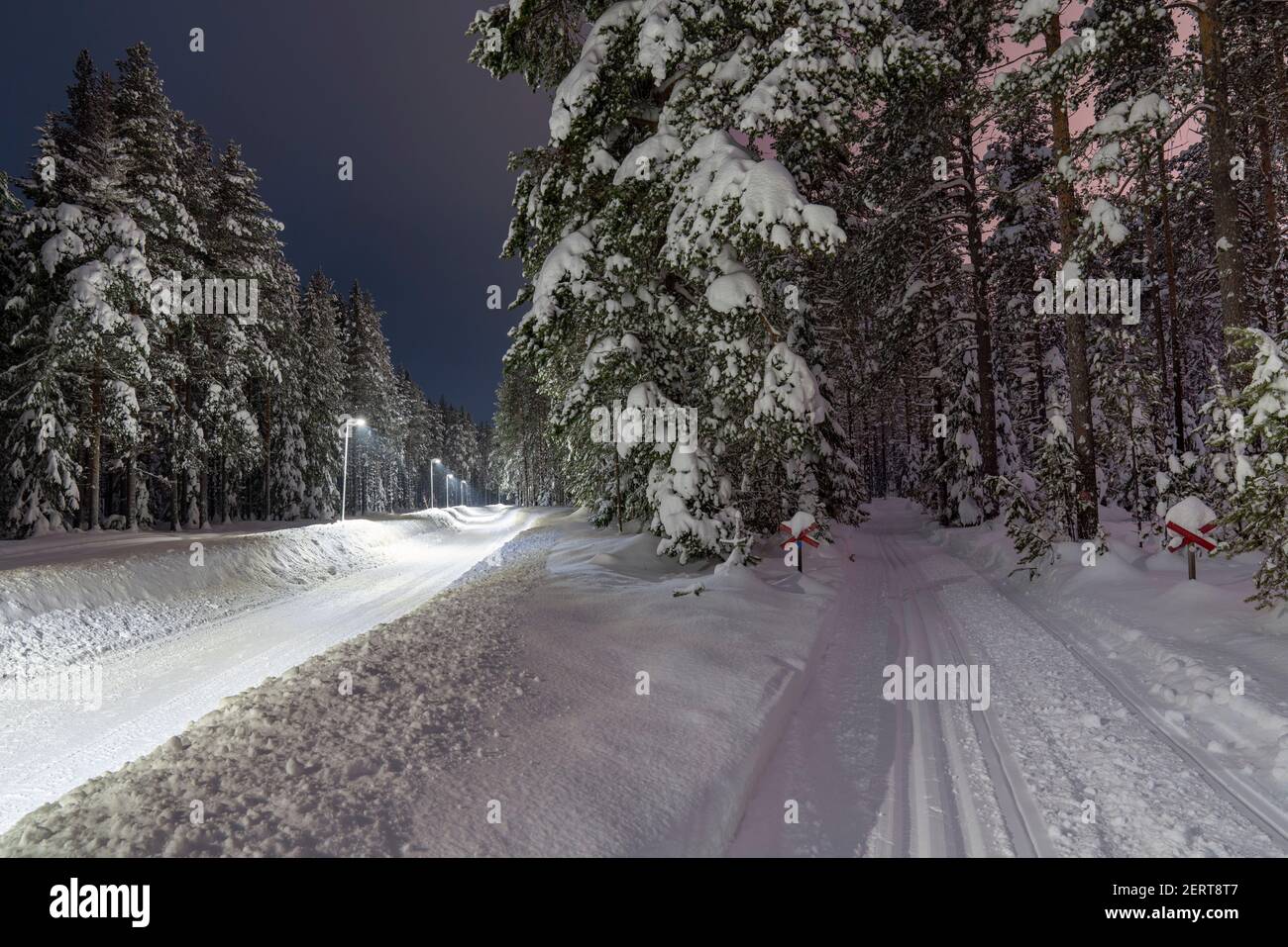Snowmobile tracks, Snow-covered walkway illuminated with street light Stock Photo