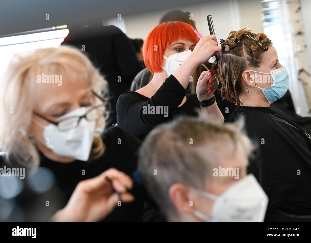 Seeheim Jugenheim, Germany. 01st Mar, 2021. Barbara Feldmann (r) from  Darmstadt-Eberstadt gets her hair cut by master hairdresser Natalie  Gröschel (2nd from left) at the "Schick Friseure" salon. After ten weeks of