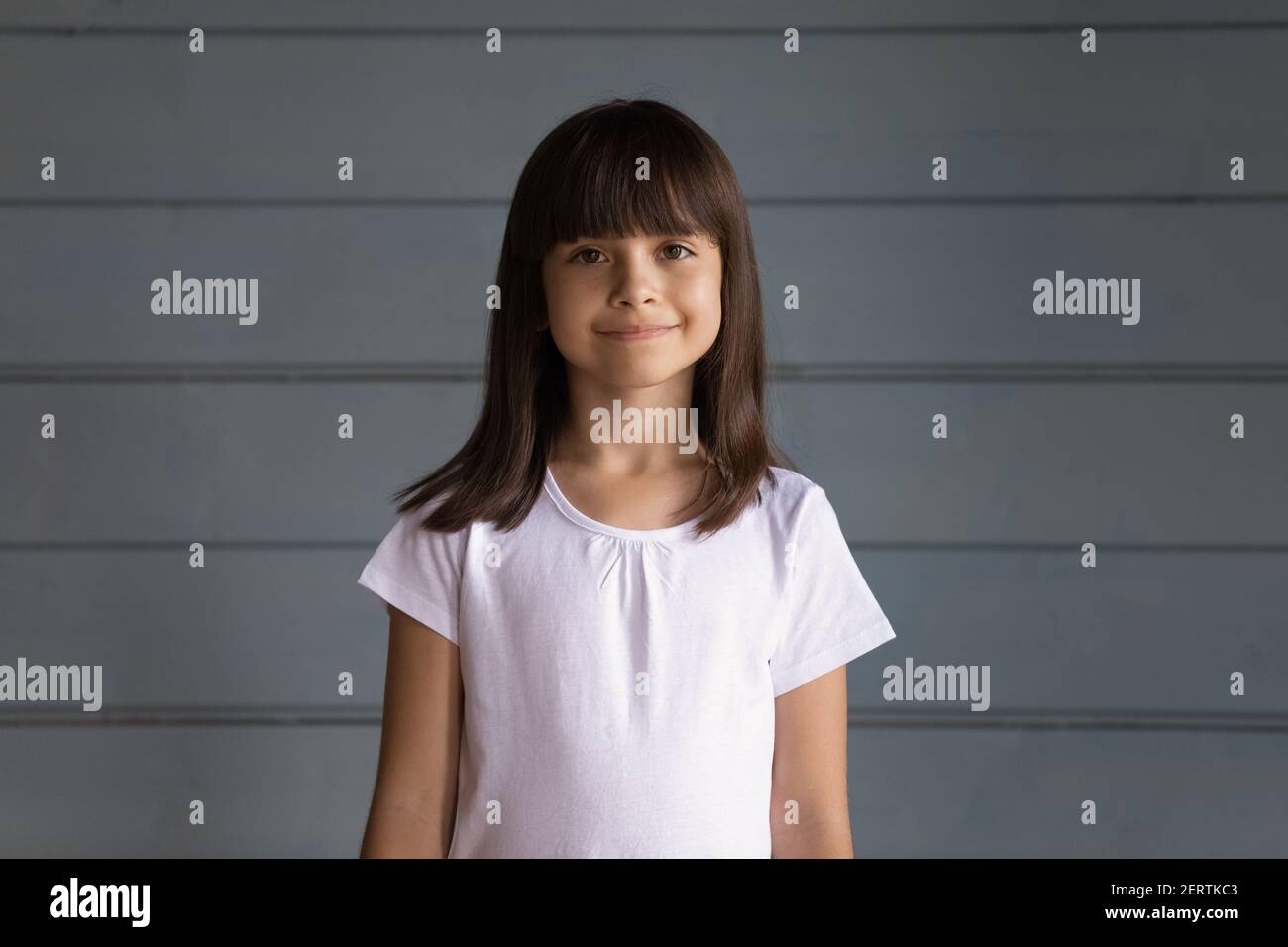 Portrait of happy small Hispanic girl on grey wall background Stock Photo