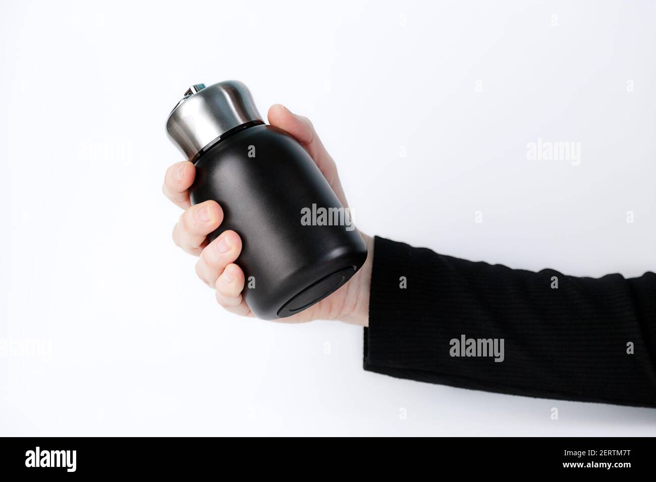Woman hand showing a black reusable, steel thermo water bottle, isolated on white background. Zero waste. Environment concept. Stock Photo