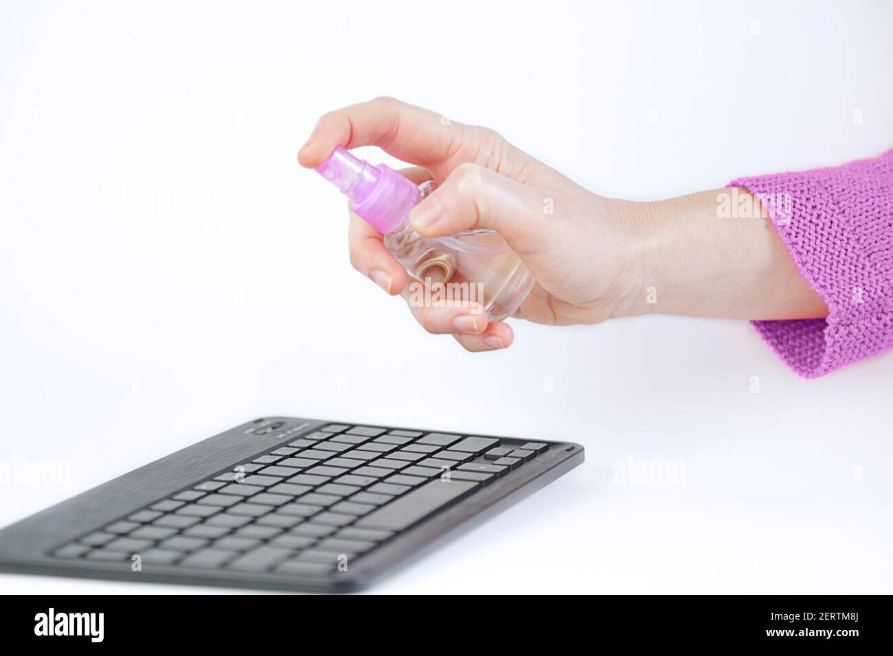 Close up of woman hands using antiseptic spray to clean her computer