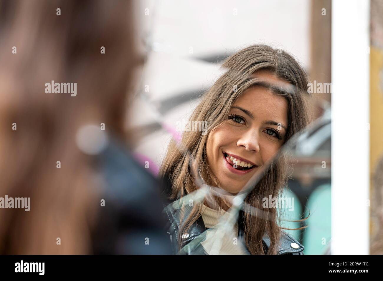 a young, positive woman looks at her reflection in a broken mirror Stock Photo