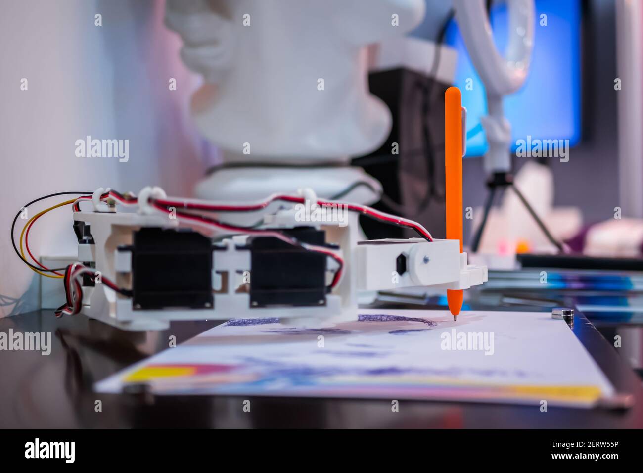 Robotic arm with orange pen drawing portrait at robot futuristic