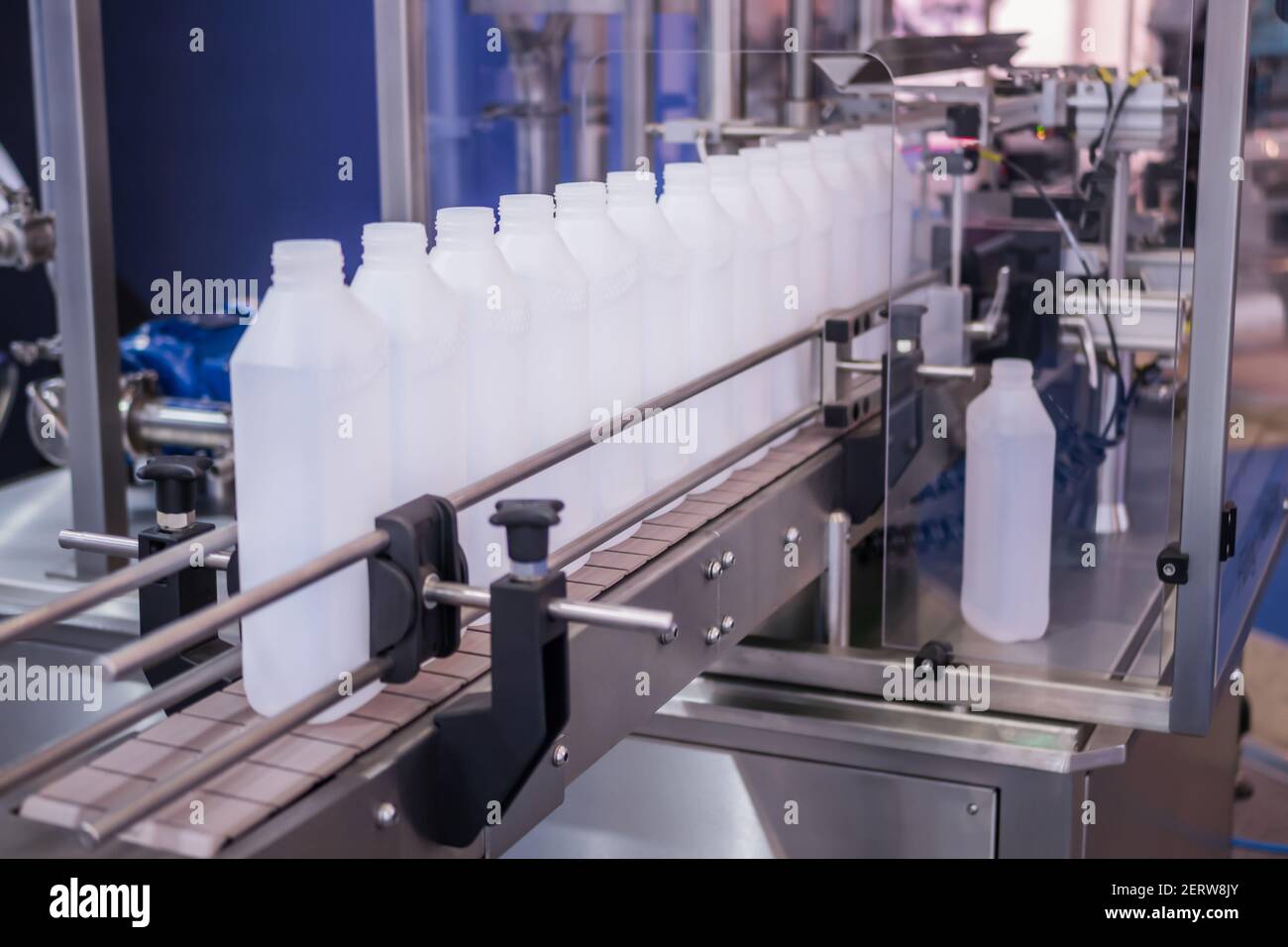 White bottles on conveyor belt of liquid filling machine Stock Photo