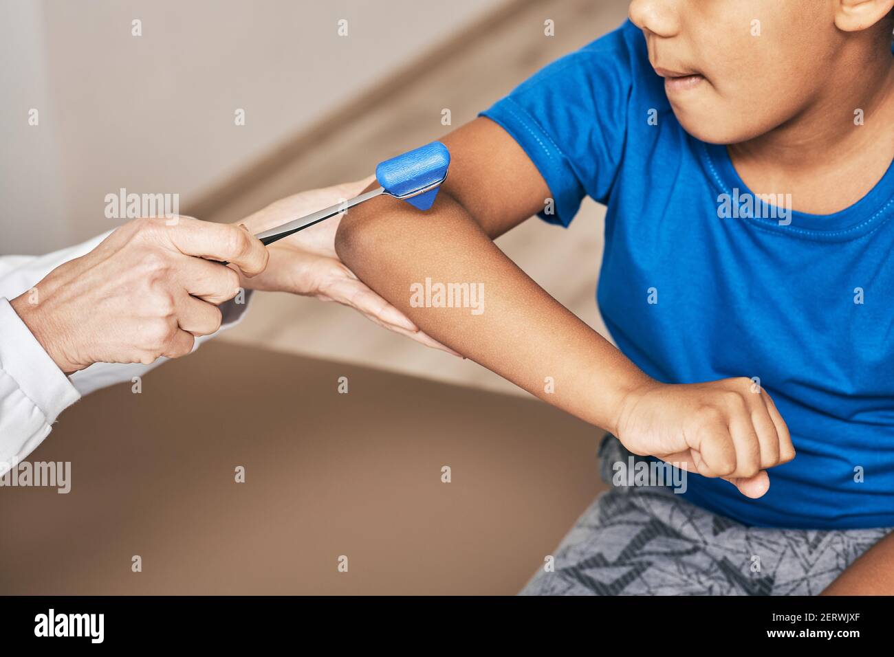 doctor uses a neurological hammer to check reflexes of the biceps muscle of the child's hand. Neurologic examination Stock Photo