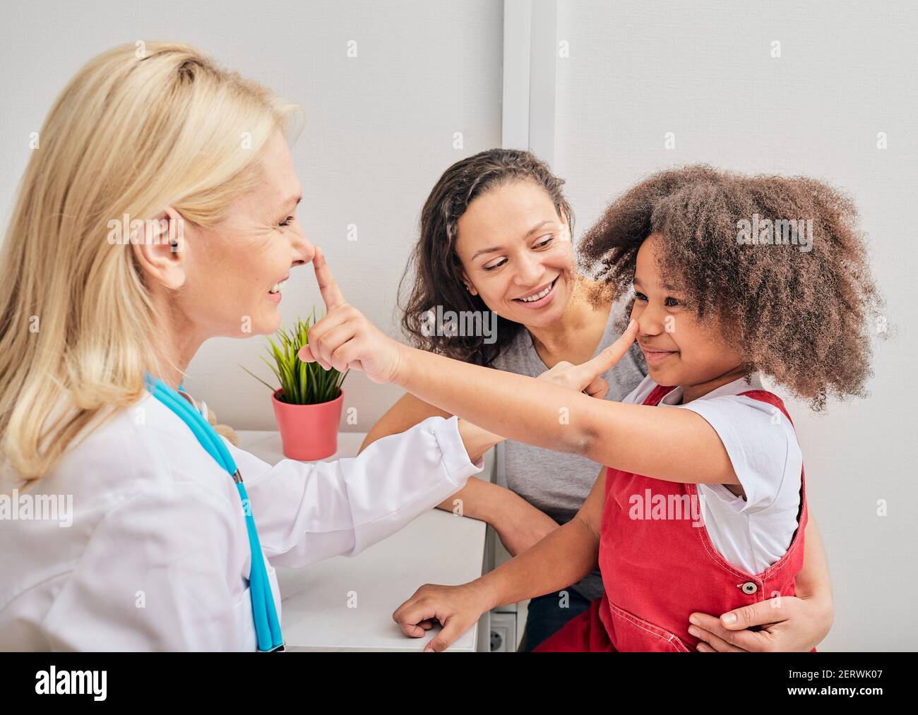 Friendly pediatrician having fun with her child patient at hospital. Consultation, kid health Stock Photo