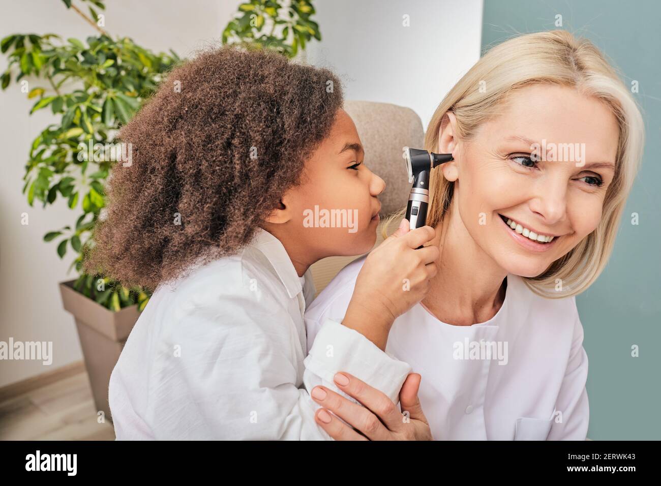 Treatment deafness for a child in a playful way. Positive little girl examining doctor with an