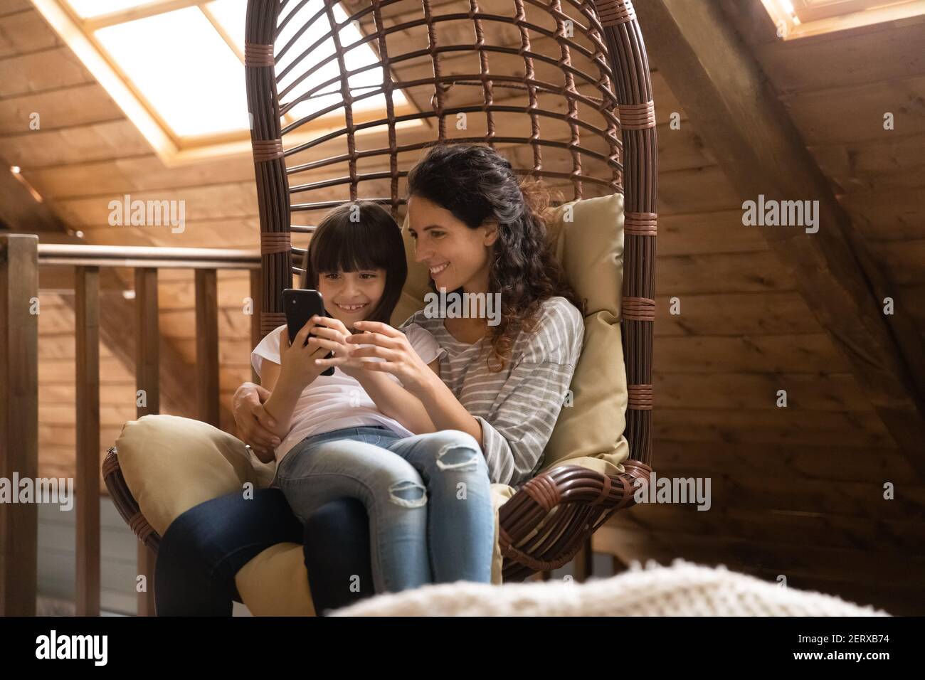 Happy Hispanic mom and daughter relax with smartphone Stock Photo - Alamy