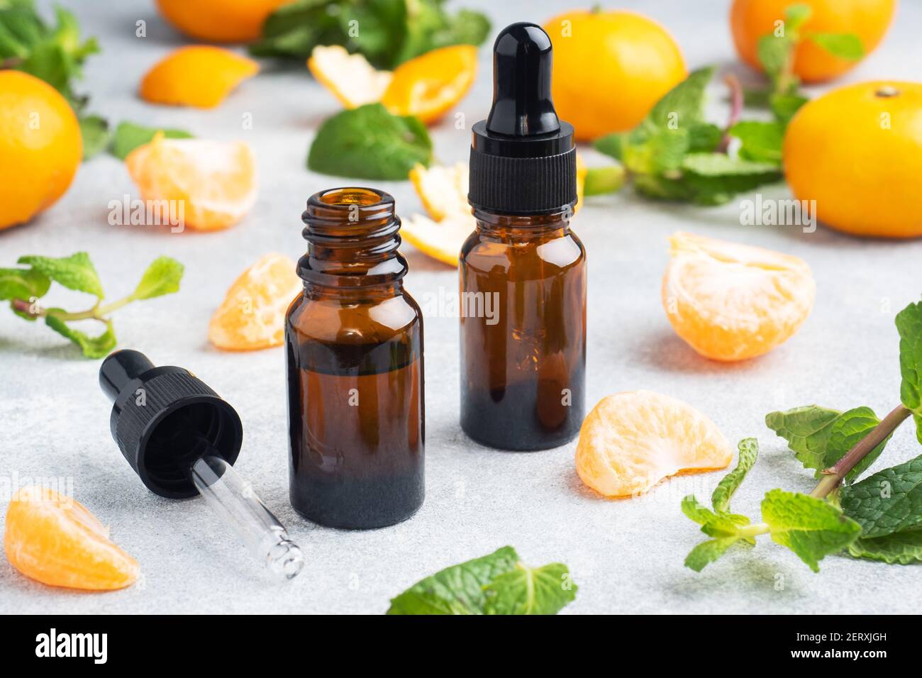 Aromatic tangerine oil in a dark bubble, cosmetic oil from Mandarin on a light gray background, copy space Stock Photo