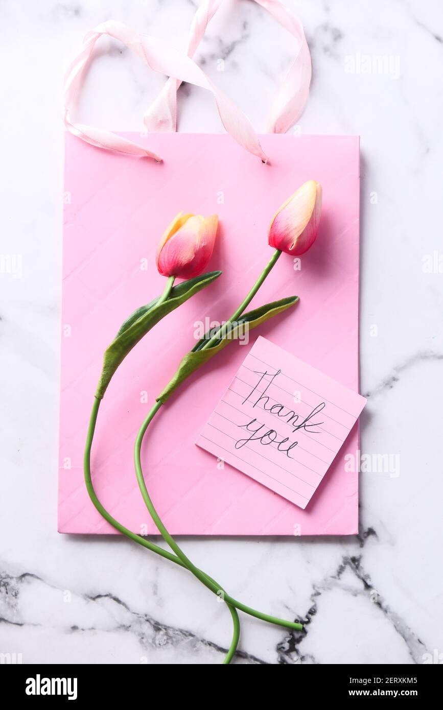 thank you message on sticky note with tulip flower on pink background  Stock Photo