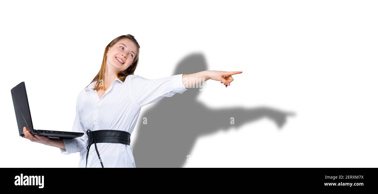 Banner,long format. Young happy girl holds a laptop laptop, looks to the side and points with her index finger. White background with shadow. Side Stock Photo