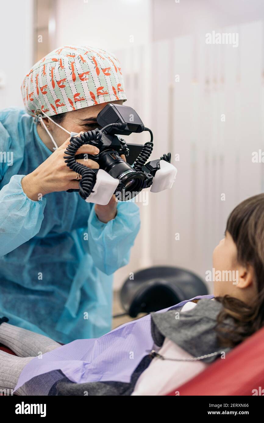 Stock photo of female dentist wearing face mask taking picture of a young patient Stock Photo