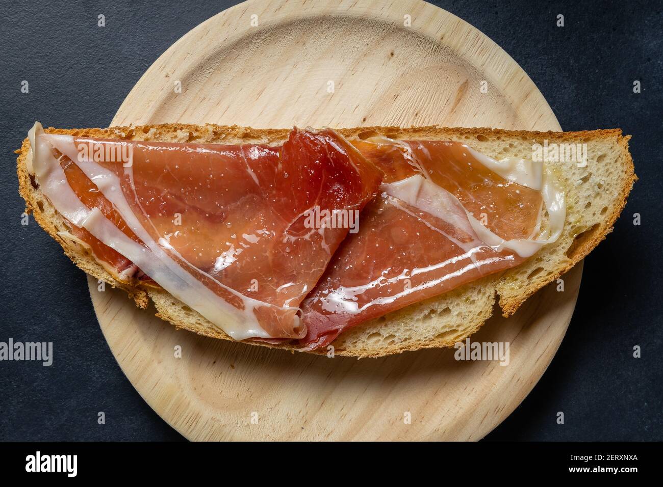 A top view of a slice of bread with olive oil and Serrano ham on a ...