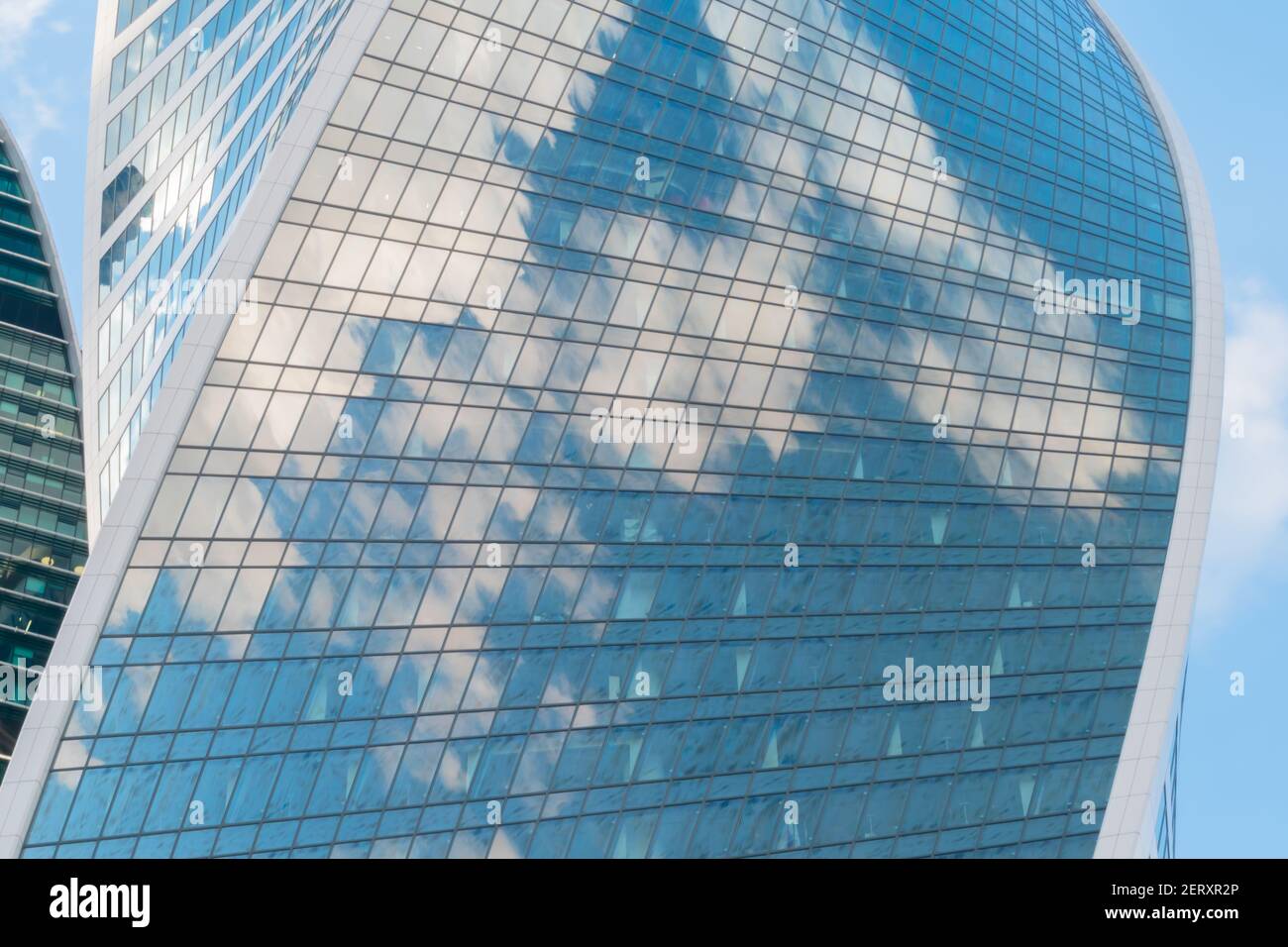 Reflection of white clouds and blue sky in glass wall of modern ...