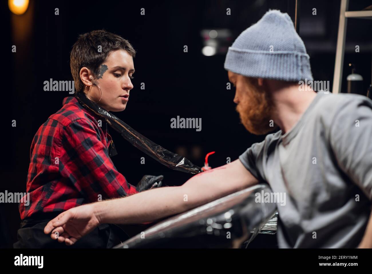 In a modern tattoo parlor, a girl with piercings and tattoos on her