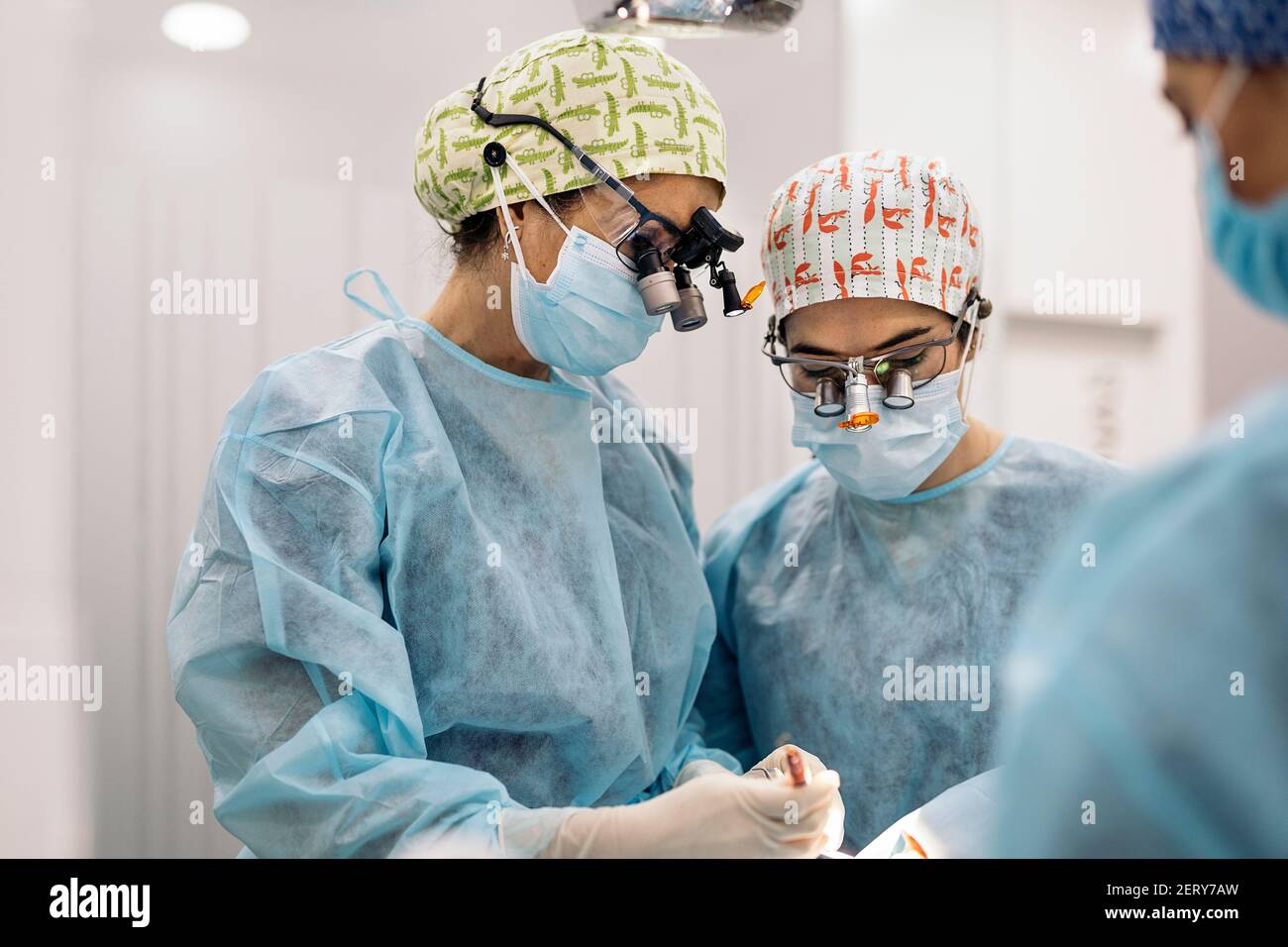 Stock photo of women team wearing face masks and dental magnifying glasses during surgery Stock