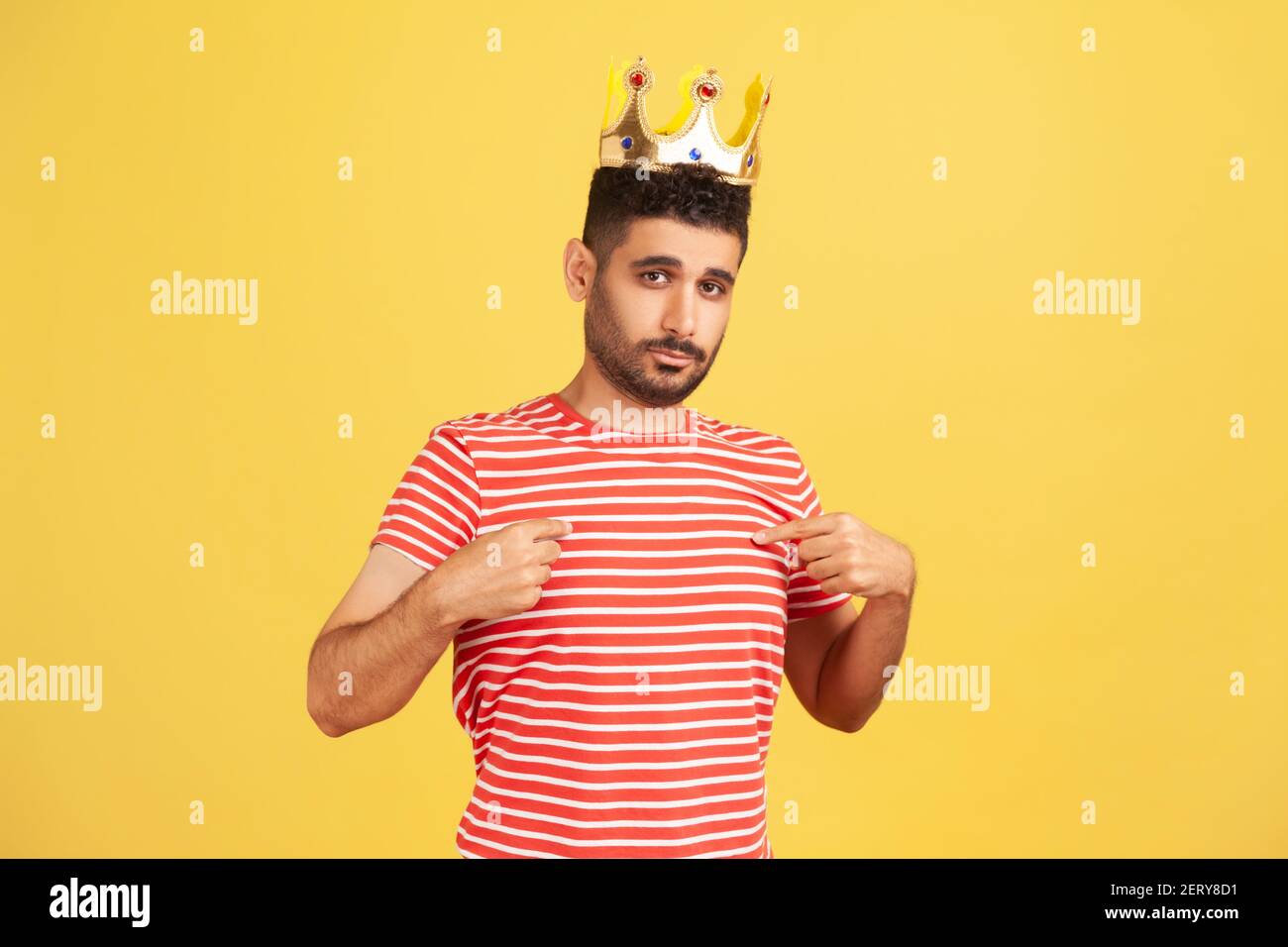 I'm king! Ambitious bearded man wearing golden crown and pointing himself, looking with arrogance, declaring his authority, superior privileged status Stock Photo