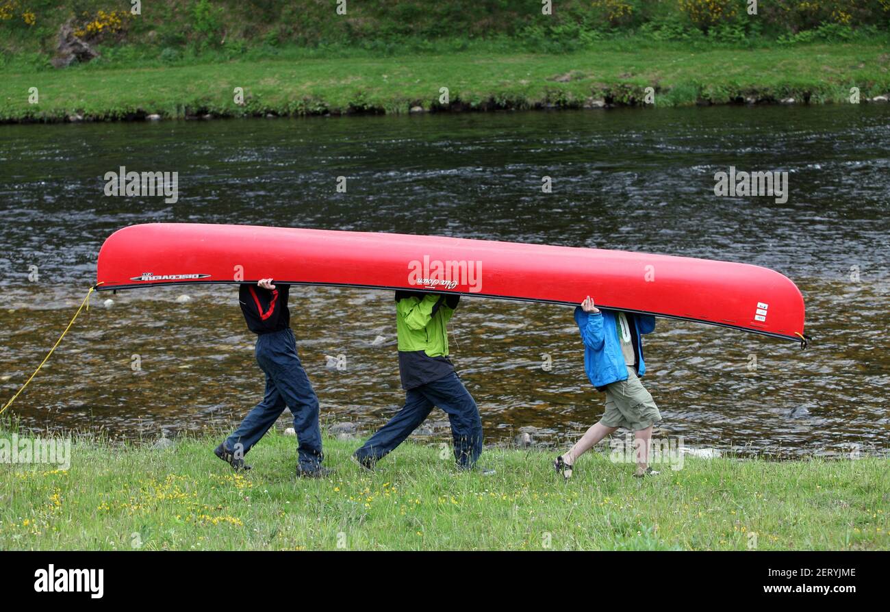 Three people carrying a canoe upside down Stock Photo Alamy